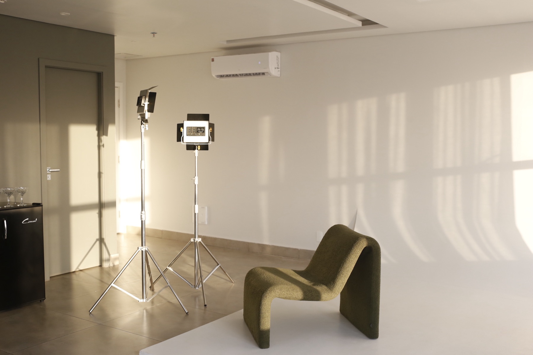 Fundo infinito branco fixo com iluminadores de LED e poltrona verde-oliva